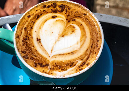 L'amour un Cappucino : Droit à la recherche vers le bas sur un Cappucino fraîchement préparés dans une tasse de chocolat en forme de coeur parsemer Pattern. Banque D'Images