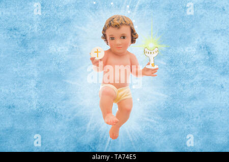 L'Enfant Jésus, Première Communion. Figurine vintage de l'Enfant Jésus avec un calice et de l'hôte sur un fond bleu. Banque D'Images