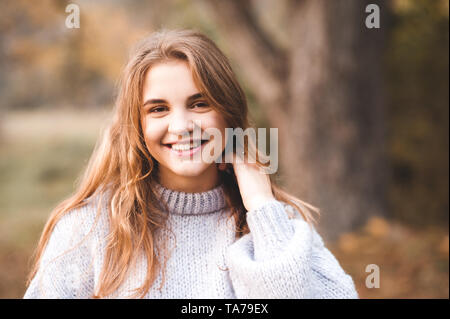 Smiling teen girl 16-17 ans portant chandail tricoté posant en gros plan du parc. Portrait of happy teenager. En regardant la caméra. 20s. Banque D'Images