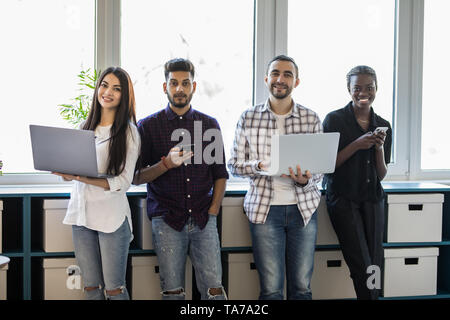 Groupe d'étudiants ou businesspeople standing in a row in office. Chat dans les réseaux sociaux de la toxicomanie en ligne avec des périphériques concept Banque D'Images