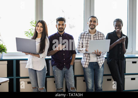 Groupe d'étudiants ou businesspeople standing in a row in office. Chat dans les réseaux sociaux de la toxicomanie en ligne avec des périphériques concept Banque D'Images