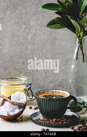 Café à toute épreuve. Diète cétonique en bleu café tasse en céramique avec le beurre de coco bio ghee et l'huile de pression à froid dans des cuillères avec des haricots et branche verte sur Banque D'Images