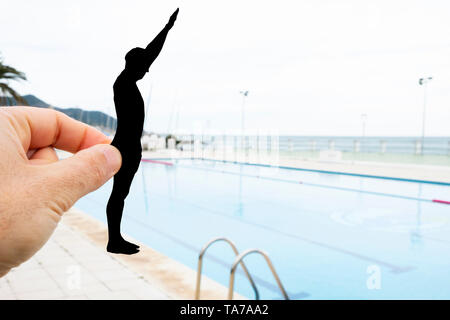 Libre de la main d'un homme avec un papier noir découpe dans la forme d'un homme sur le point de se jeter dans une piscine Banque D'Images