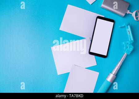 Smartphone avec écran vide et des photos sur un fond bleu. Maquette, mise à plat Banque D'Images