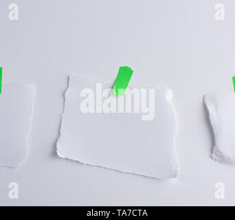 Arrachée morceau de papier blanc collé à velcro vert, fond blanc Banque D'Images