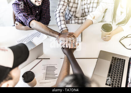 Mettre les mains ensemble, l'équipe connexion show et d'alliance, vue du dessus de la table de travail. Teambuilding dans office, les jeunes hommes et les femmes d'unir dans une ambiance décontractée Banque D'Images