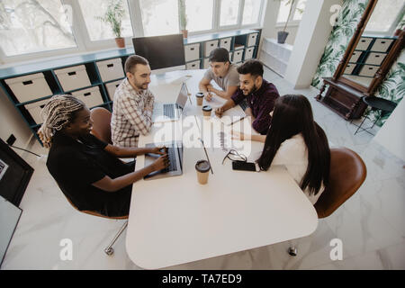 Les jeunes gens créatifs multiraciale dans un bureau moderne. Groupe de jeunes gens d'affaires travaillent ensemble avec ordinateur portable, tablette, téléphone intelligent, ordinateur portable. Banque D'Images