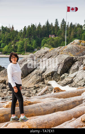 Très jeune grand-mère marche sur billes de bois flotté sur la Sunshine Coast de la Colombie-Britannique, Canada Banque D'Images