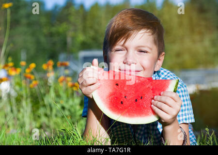 Funny boy eats watermelon parc extérieur en été, des aliments sains Banque D'Images