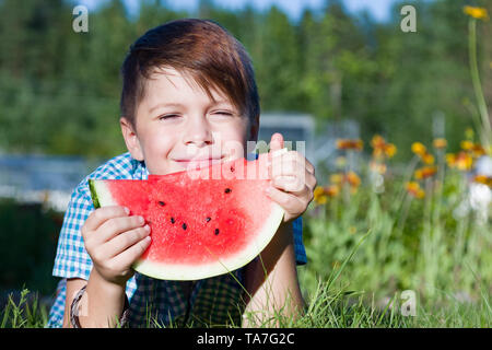 Funny boy eats watermelon parc extérieur en été, des aliments sains Banque D'Images