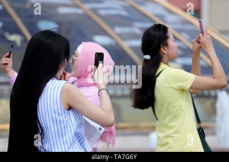 Happy asian et des filles musulmanes faire un avec les smartphones selfies sur Manege square, selective focus. Les personnes qui utilisent les téléphones mobiles, les jeunes femmes à prendre des photos Banque D'Images