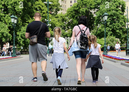 Une famille avec des enfants de marcher dans un parc de la ville, vue arrière. Couple avec deux filles en été, concept de parentalité, famille loisirs et voyages Banque D'Images