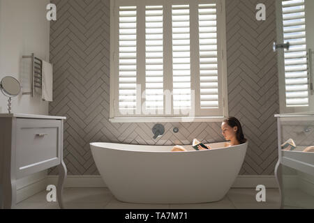 Belle femme lisant un livre dans la baignoire Banque D'Images