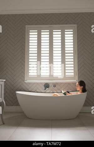 Belle femme lisant un livre dans la baignoire Banque D'Images