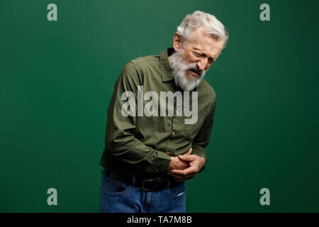 Vieil homme a mal au ventre. senior man with closed eyes de toucher son ventre.la photo en gros. studio shot. problème de santé. sa vieillesse Banque D'Images