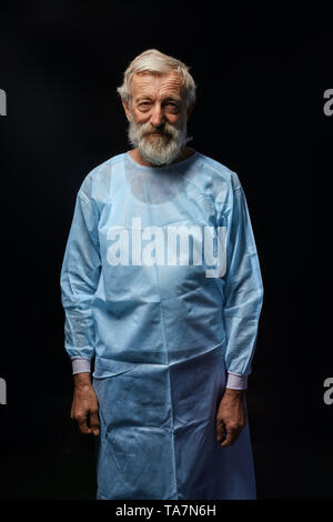 Beau vieux médecin qualifiés professionnels en uniforme spécial posant pour l'appareil photo. la photo en gros. fond noir isolé.job, occupation, professio Banque D'Images