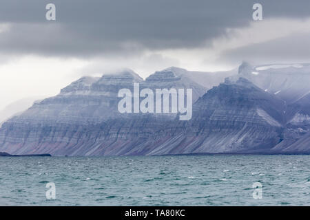 Billon ans formations rocheuses dentelées avec différentes mousse verte et de neige à l'intérieur, Svalbard, Norvège, Isfjorden Banque D'Images