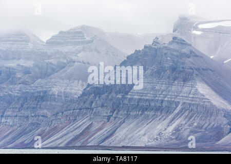 Billon ans formations rocheuses dentelées avec différentes mousse verte et de neige à l'intérieur, Svalbard, Norvège, Isfjorden Banque D'Images