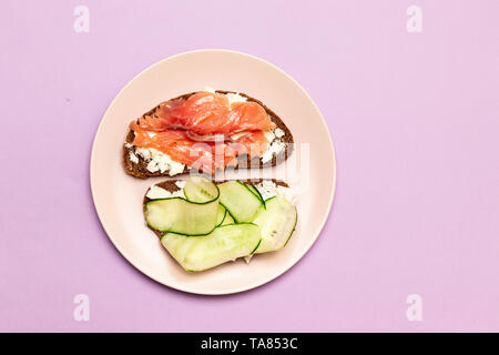 Le petit déjeuner du matin de sandwichs assortis avec différents matériaux sur une planche de bois. Sandwich de poisson avec du fromage et de concombre sur l'arrière-plan. Banque D'Images