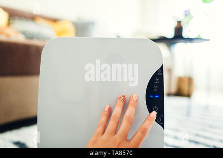 Femme active sur l'utilisation du déshumidificateur panneau tactile à la maison. Pour le nettoyage de l'appareil moderne airdryer air. Close up Banque D'Images