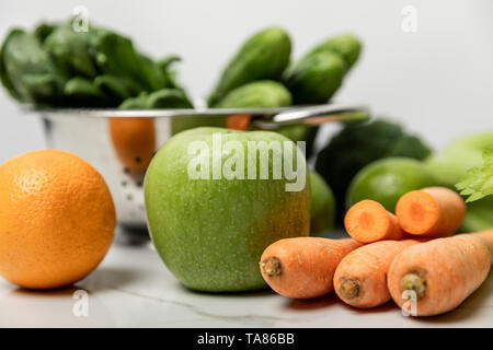 Focus sélectif de vert pomme, orange et carotte concombre vert sur blanc près de Banque D'Images