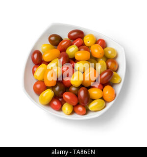 La plaque avec un mélange de petites tomates mûres colorées isolé sur fond blanc Banque D'Images