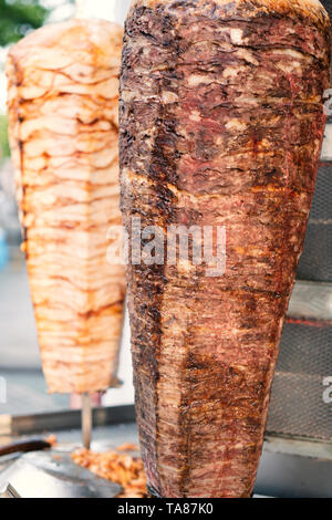 Deux brochettes de poulet et d'agneau en rotation grillé de la viande en acier inoxydable grill et prêt à servir dans un fast food du Moyen-Orient Sandwich kebab Banque D'Images