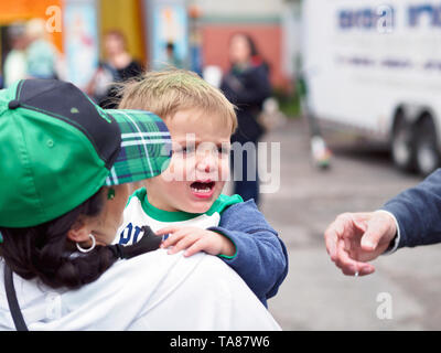 Un petit garçon est en train de pleurer comme sa mère le tient au jour de la Saint Patrick 2019 Block Party à Corpus Christi, Texas USA. Banque D'Images