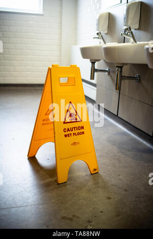 Attention plancher mouillé en jaune support de sécurité panneau d'avertissement dans une toilette. Banque D'Images