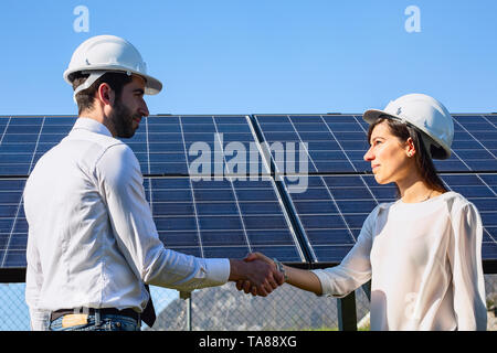 Les ingénieurs de la chemise de leur serrer la main. Arrière-plan de panneaux photovoltaïques Banque D'Images