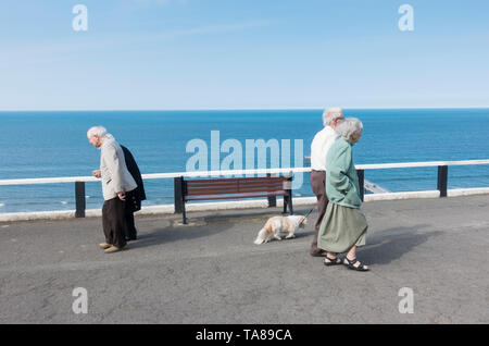 Les couples âgés marchant le long promenade surplombant la mer. UK Banque D'Images