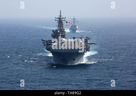 La classe Wasp américaine navire d'assaut amphibie USS Kearsarge, avant, et la classe Arleigh Burke destroyer lance-missiles USS Bainbridge voile en formation dans le cadre du Groupe d'attaque le 17 mai 2019, dans la mer d'Oman. Le groupe fait partie des forces additionnelles d'être envoyé au Moyen Orient pour lutter contre ce que l'administration d'Atout appelle des indications claires de menaces de l'Iran. Banque D'Images