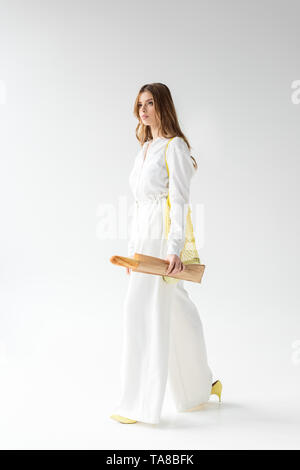 Jolie femme marchant avec baguette en sac de papier jaune et blanc sur le sac de chaîne Banque D'Images