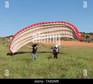 L'instructeur de vol de sexe féminin, l'enseignement d'une femme de décoller avec un parapente sur le terrain lors d'une journée ensoleillée de ciel bleu Banque D'Images