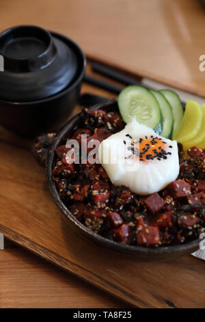 Steak de thon sur le riz avec des oeufs sur table en bois de style japonais Banque D'Images