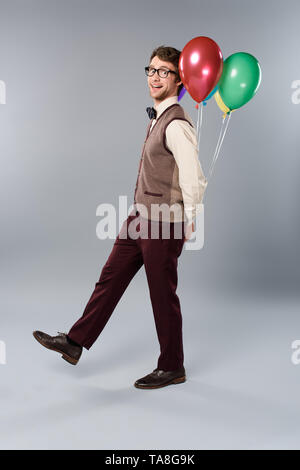 L'homme drôle en tenant des verres ballons multicolores sur fond gris Banque D'Images