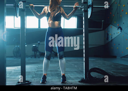 Gymnaste girl doing squat barbell. Vue avant de l'attractive young woman Banque D'Images