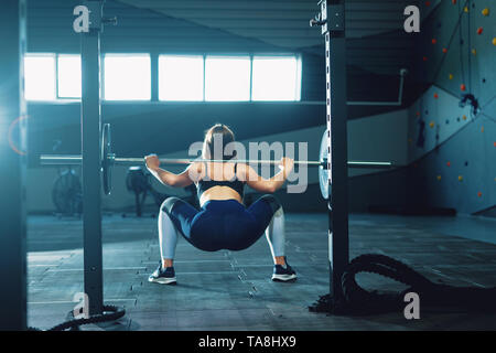 Gymnaste girl doing squat barbell. Vue avant de l'attractive young woman Banque D'Images