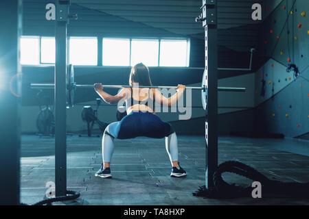 Gymnaste girl doing squat barbell. Vue avant de l'attractive young woman Banque D'Images