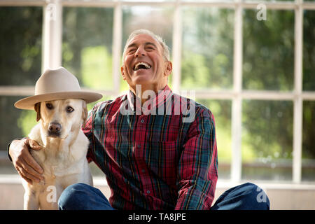 Happy senior man sitting avec son bras autour de son chien. Banque D'Images