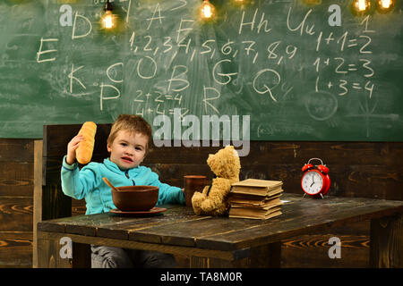 Élève à manger table en bois. Élève peu profiter de la pause déjeuner dans la salle de classe. Menu scolaire pour élève. Aujourd'hui, c'est élève, demain, c'est président Banque D'Images