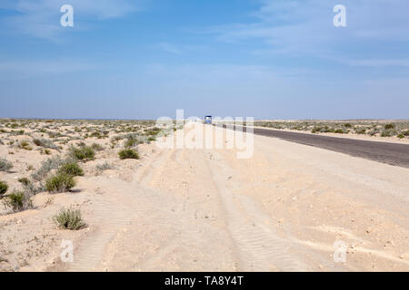 Entraîneur touriste passager roulant dans la distance à l'autoroute déserte sur le lac séché sel, route de l'Algérie à la Tunisie le Chott el Jerid salt flat. L Banque D'Images