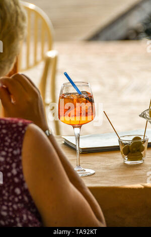 GARDA, Lac de Garde, ITALIE - Septembre 2018 : personne assise à une table dans un café en garda sur le lac de Garde avec une boisson glacée Aperol Spritz Banque D'Images