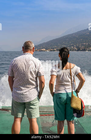 GARDA, Lac de Garde, ITALIE - Septembre 2018 : deux personnes debout à l'avant d'un traversier pour passagers dans un voyage sur le lac de Garde avec des vagues et des embruns. Banque D'Images