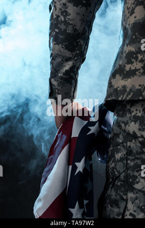 Portrait de soldat holding american flag sur noir de fumée Banque D'Images