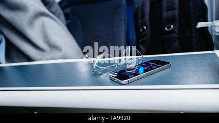 Londres, Royaume-Uni - Mar 11, 2017 : l'accent sur optique lunettes titane avec nouveau smartphone iPhone moderne sur table à l'intérieur du train train britannique Banque D'Images