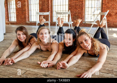 Portrait de groupe de jeunes excités sportive de belles filles avec des tapis d'entraînement debout à côté de mur blanc rire et parler ensemble Banque D'Images