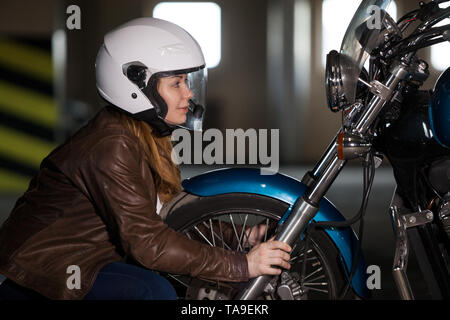 Femme biker à projecteur de moto et en se tenant la main, roue garrage souterraine Banque D'Images