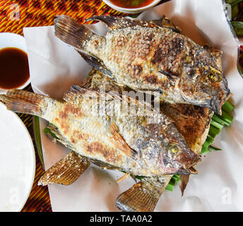 Le poisson tilapia grillé sur herbe avec le sel et la sauce chili sur la plaque en Asie Thai style poissons cuits brûler Banque D'Images
