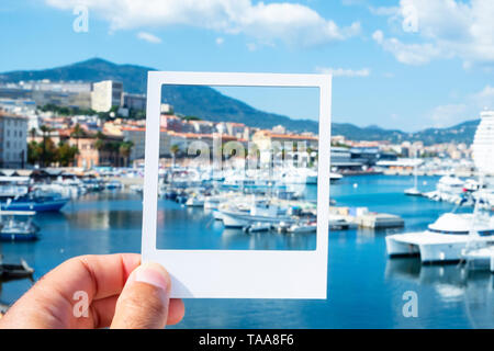 Libre d'un jeune homme de race blanche avec un cadre blanc dans sa main, au port d'Ajaccio, simulant une photographie instantanée Banque D'Images